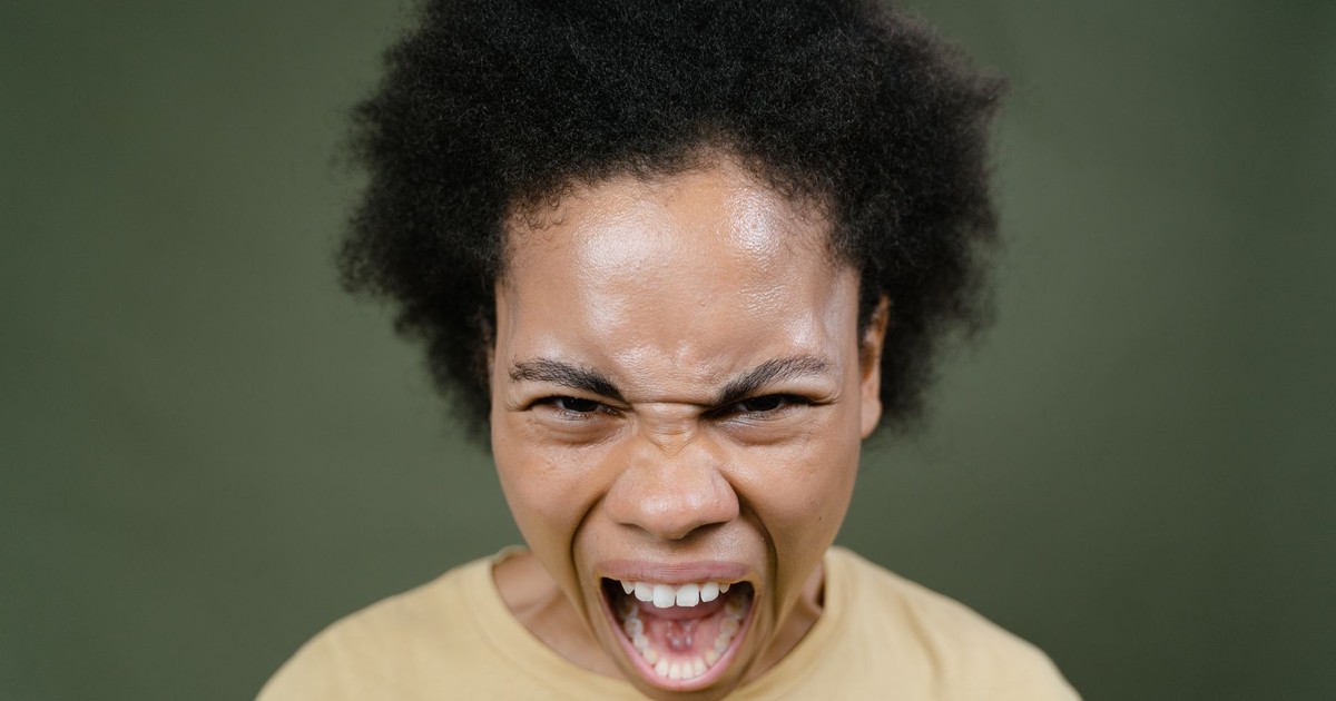 Close-up of an African American woman with afro hair expressing anger in a studio setting.