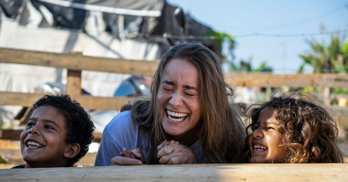 A woman and children sharing laughter outdoors in Goiânia, Brazil, under the sun.