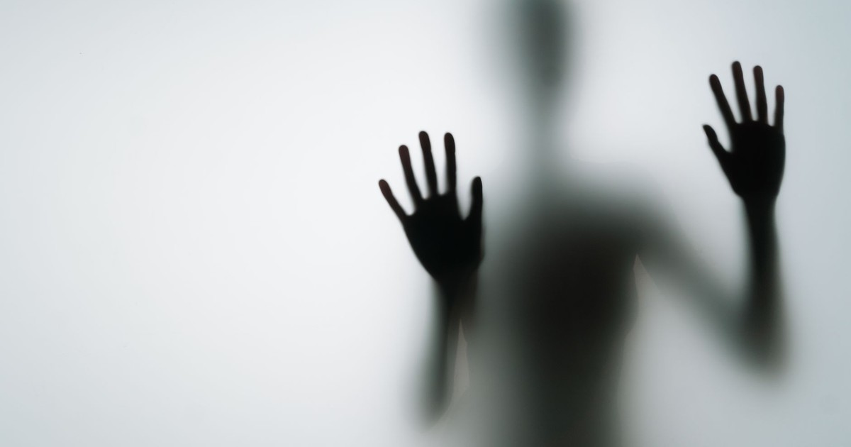 Abstract silhouette of person with hands against glass, creating a mysterious vibe.