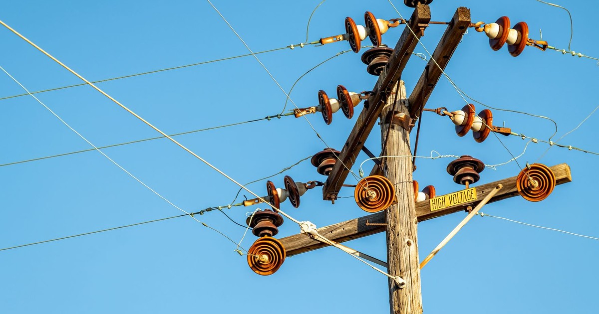 High voltage power line and insulators captured against a clear blue sky.