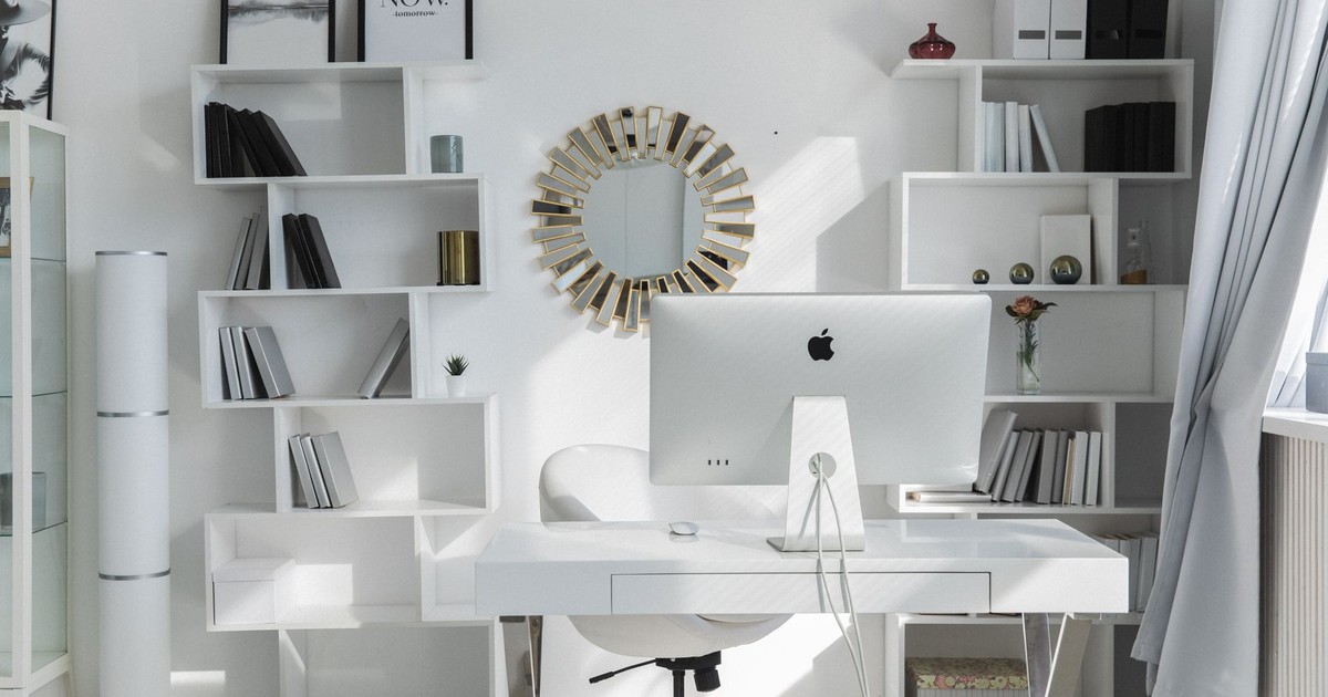 Bright minimalist home office setup with white shelves, desk, and iMac. Ideal for productivity.