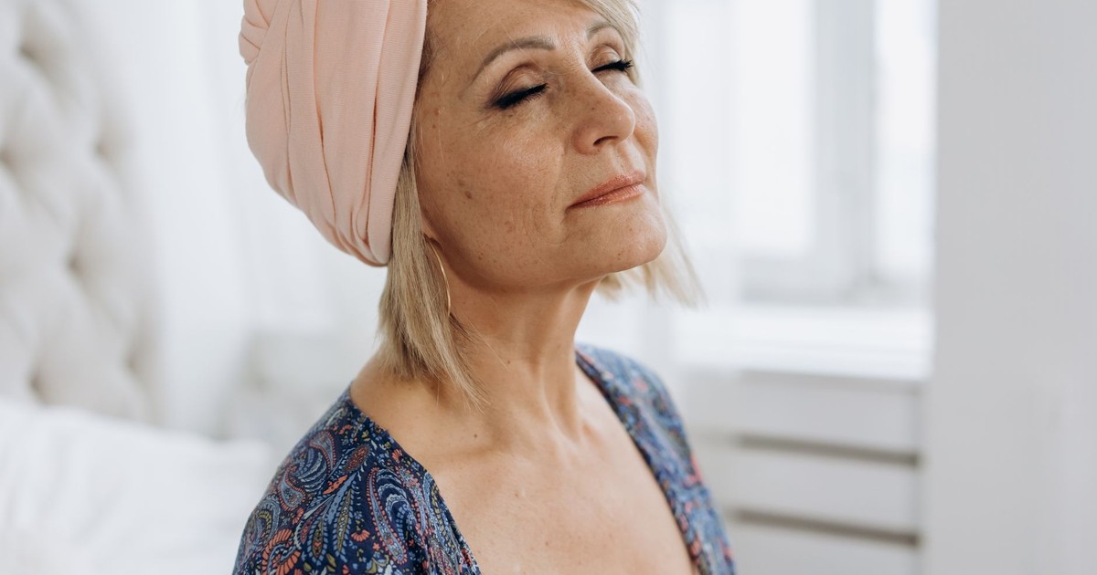 Peaceful mature woman with closed eyes and headscarf, meditating indoors.