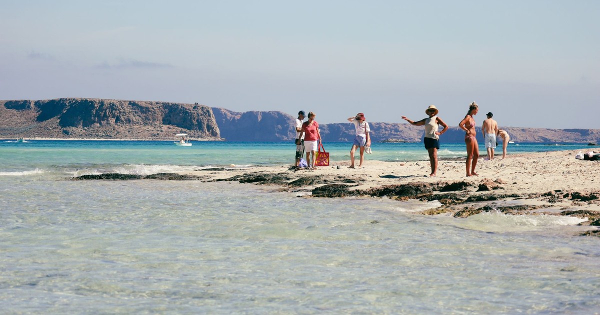 A sunny day at Balos Lagoon in Greece with people enjoying the beach and clear blue waters.