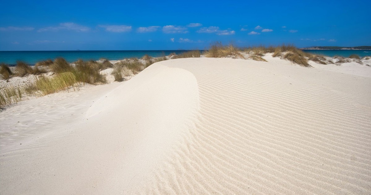Pristine white sand dunes and clear blue sky at Porto Pino beach, Sardinia.
