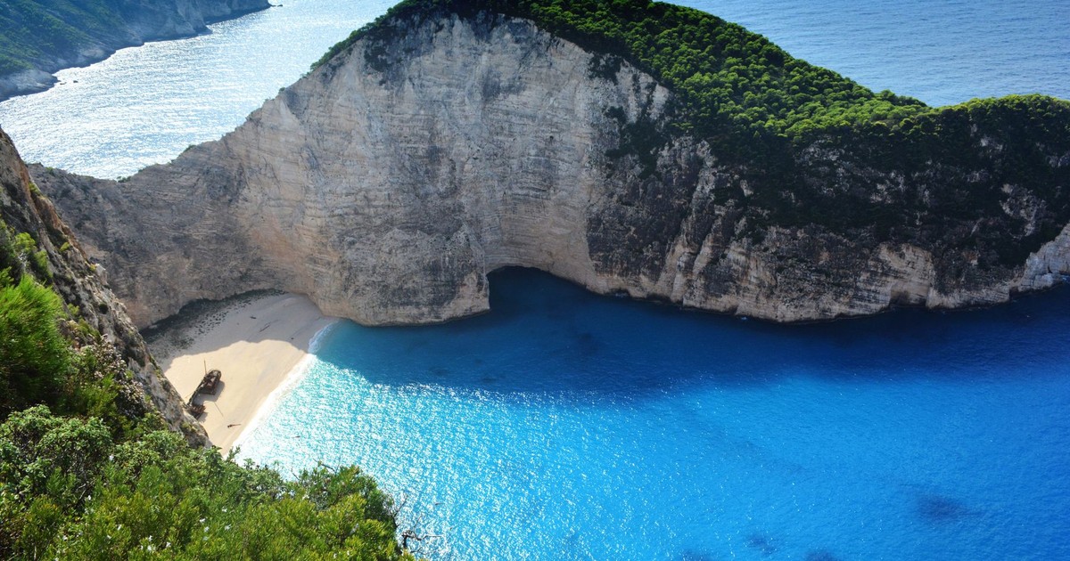 A breathtaking aerial view of Navagio Beach with turquoise waters and lush greenery.
