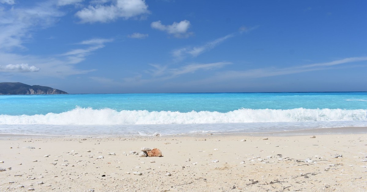 Serene beach view at Myrtos Beach, Kefalonia, Greece with clear blue skies and turquoise waters.