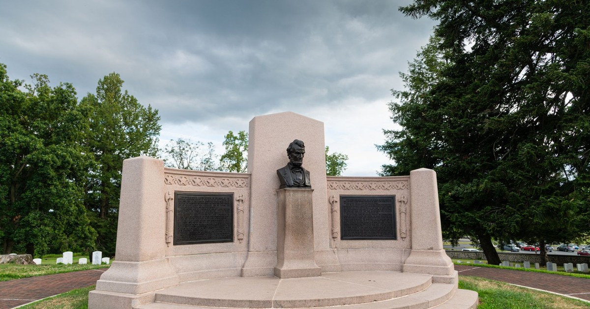 Lincoln Bust at Gettysburg Soldiers' National Monument amid lush greenery under cloudy skies.