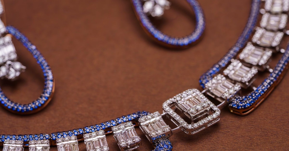 Close-up of an exquisite blue sapphire and diamond necklace and earrings against a brown background.