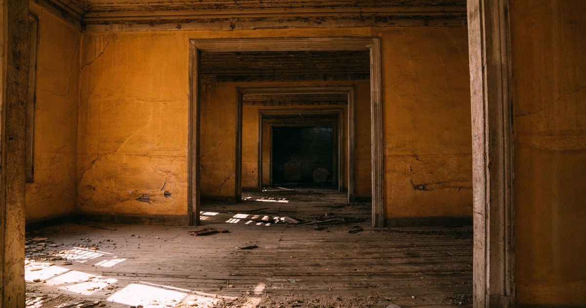 Explore the eerie beauty of an abandoned building's sunlit interior and shadows.