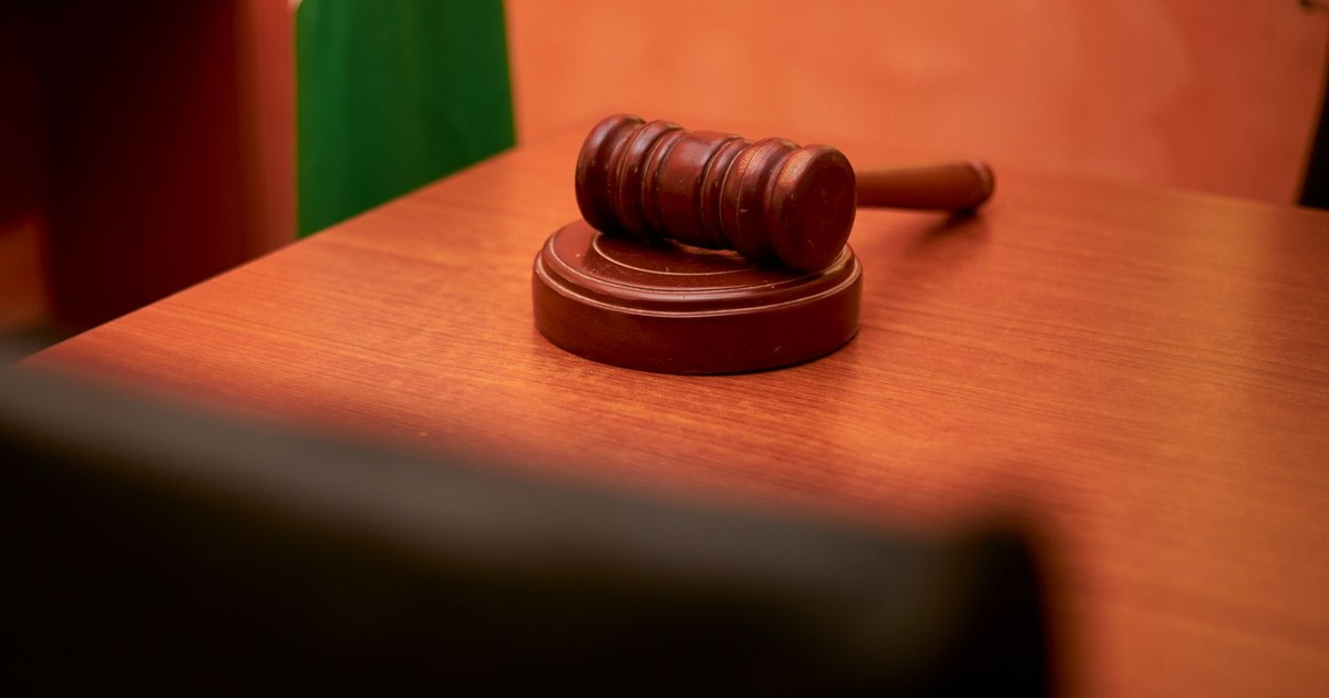 A close-up of a gavel on a courtroom desk representing law and justice.