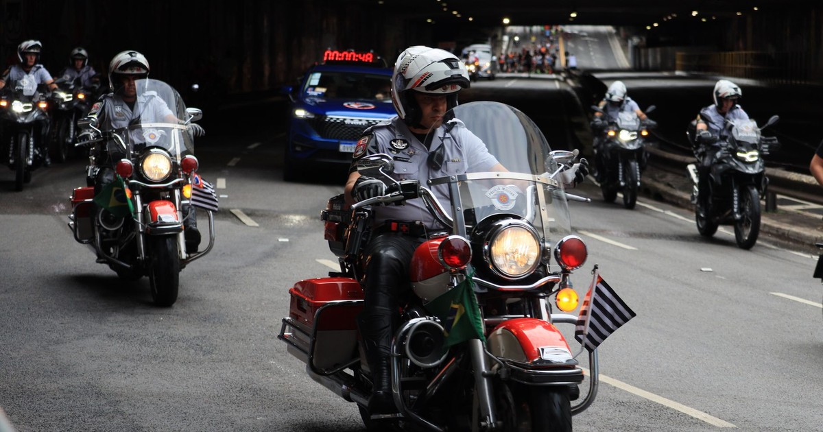 Police officers on motorcycles lead a parade through an urban tunnel, showcasing unity and law enforcement presence.