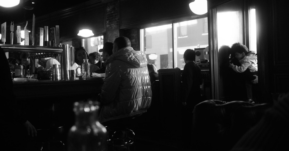 Moody black and white photo of a busy Chicago café bar with people inside.