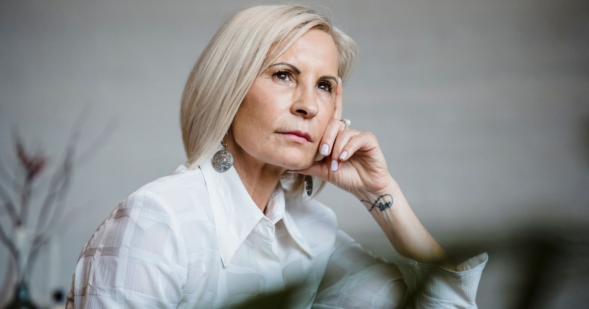 Portrait of a well-dressed senior woman lost in pensive thought indoors.