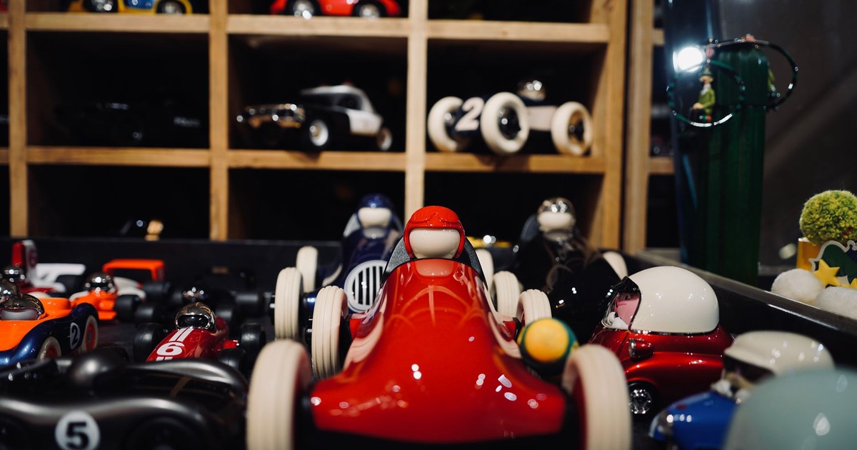 A vibrant assortment of miniature vintage race cars showcased in a wooden display case.