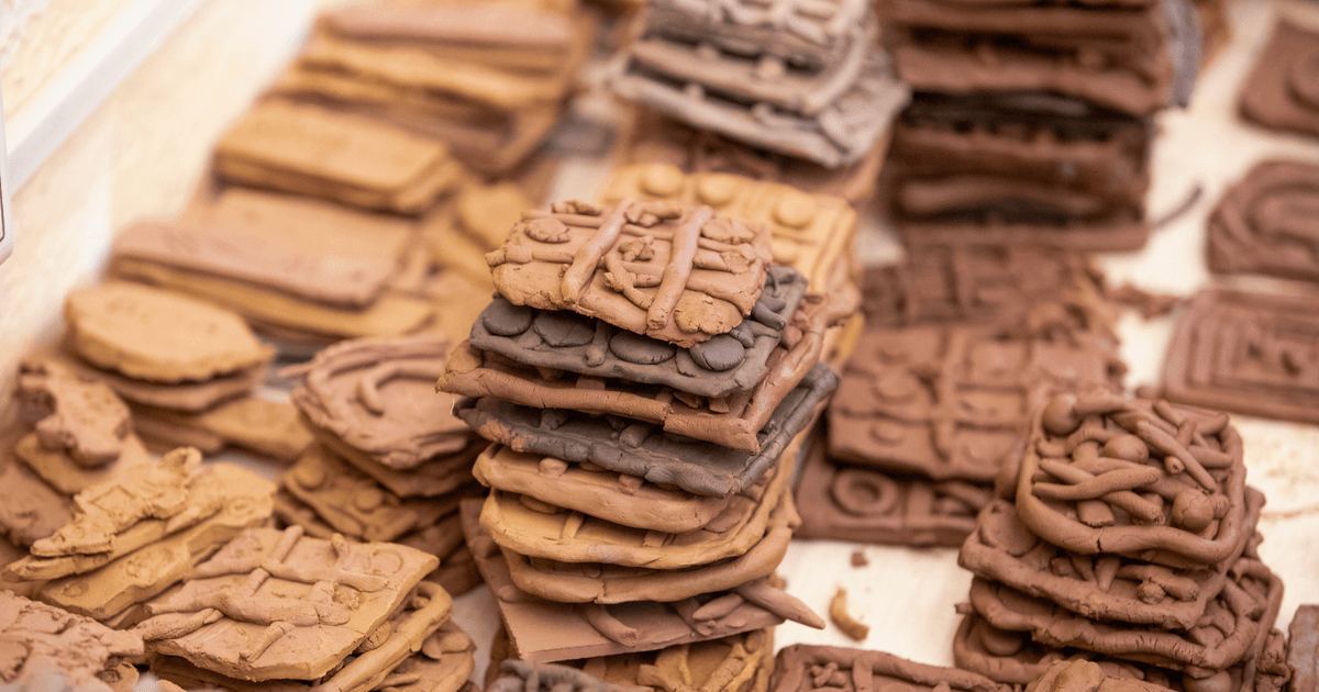 Close-up of stacked clay tablets with intricate, ancient designs in various shades of brown.