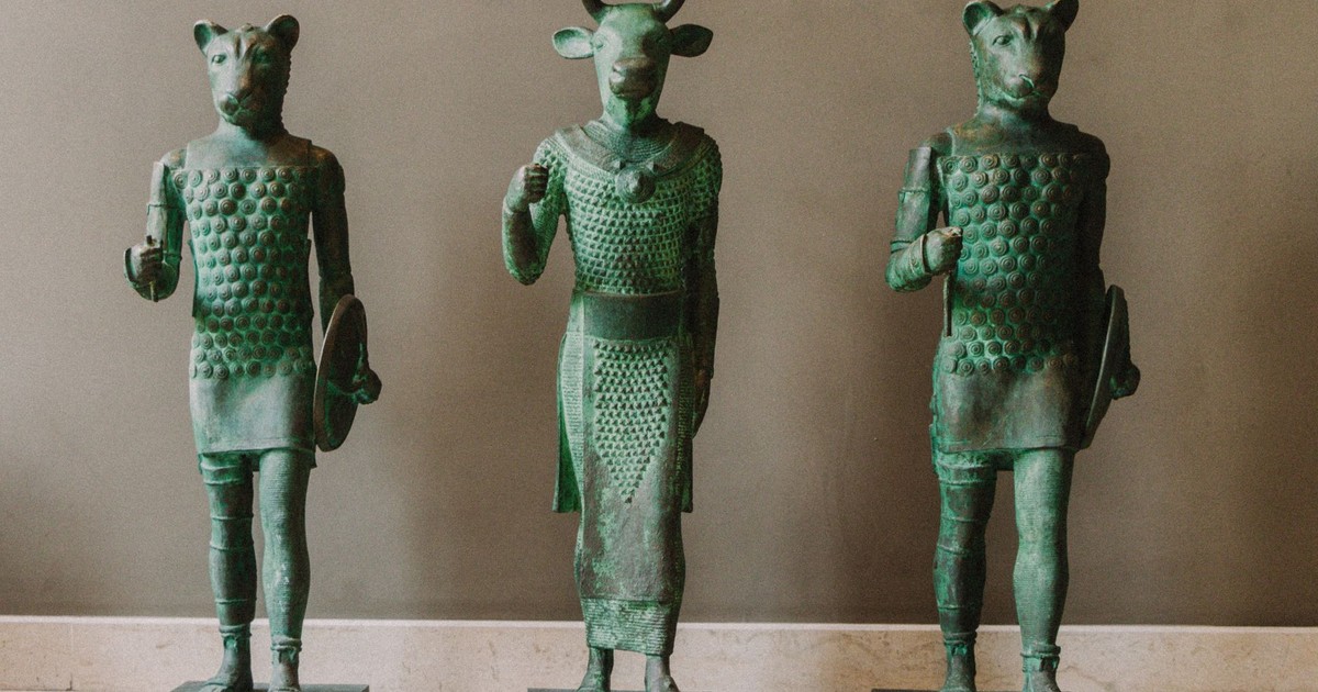 Bronze statues depicting ancient horned and animal figures in a museum setting.