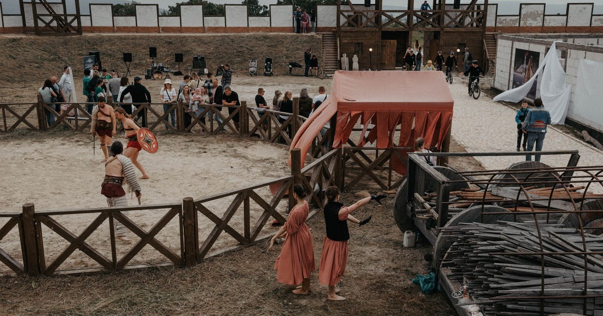 Lively medieval reenactment event featuring gladiators and spectators in outdoor arena.