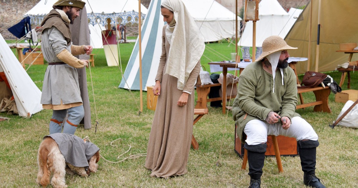 People dressed in medieval attire at a historical reenactment event outdoors.