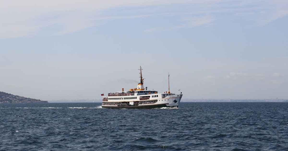 A passenger ferry cruises through the calm waters under a clear sky.