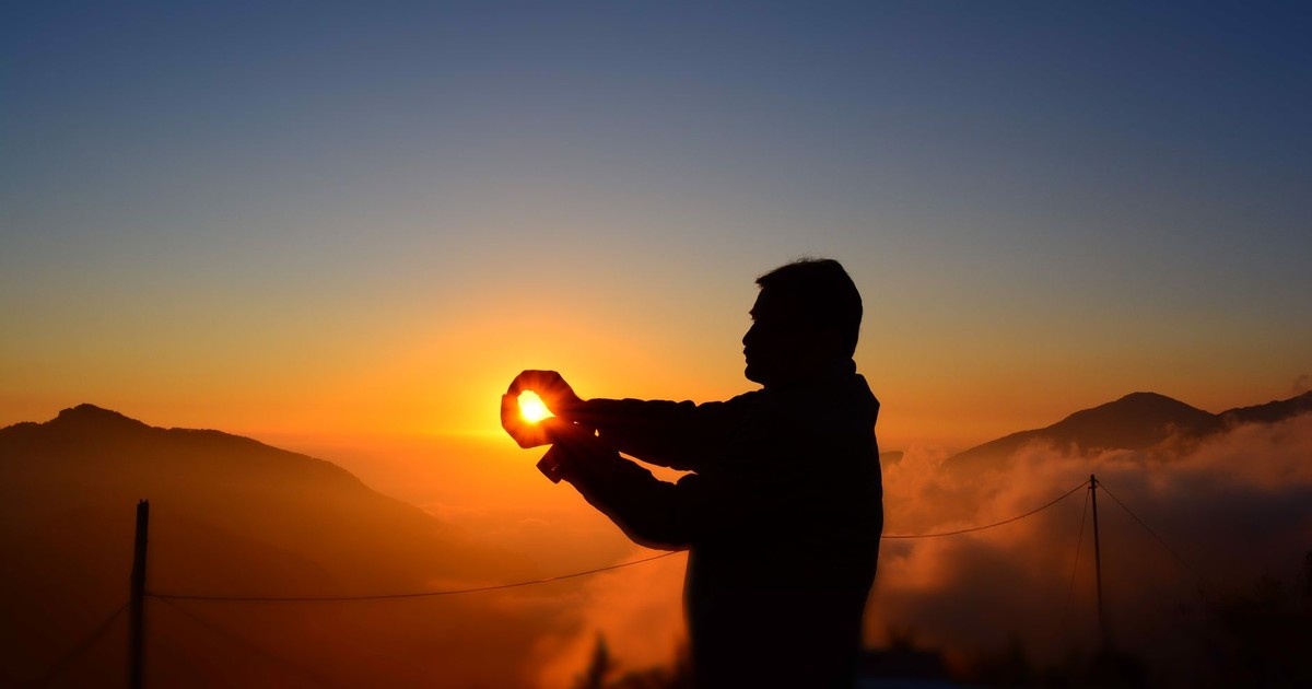 A captivating silhouette of a man capturing the sunrise over foggy mountains.