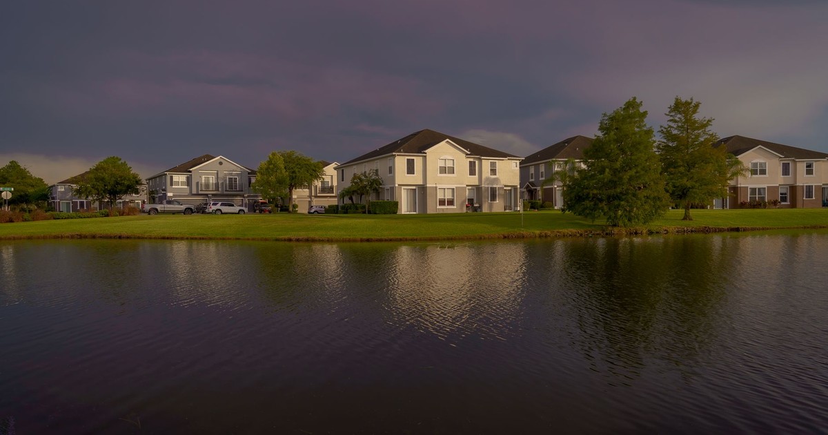Scenic view of lakefront homes reflecting on water under a dramatic sky in Orlando.