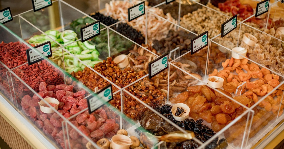 A vibrant selection of dried fruits in transparent containers at a market stall.