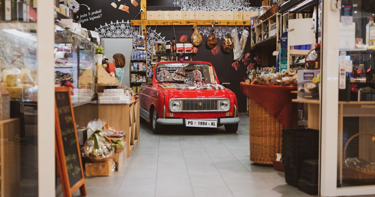A vintage red car creatively displayed inside a cozy grocery store in Zagreb, Croatia.