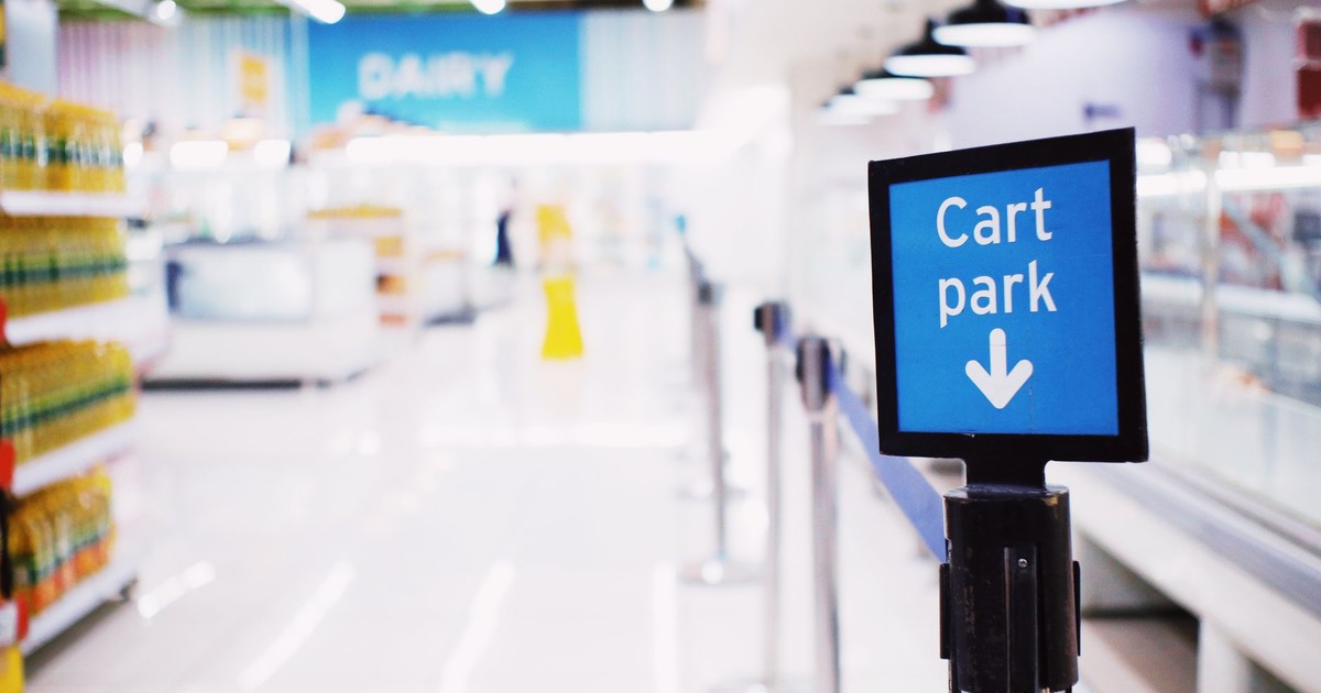 Blue signboard with inscription Cart park placed near counter with products in contemporary supermarket