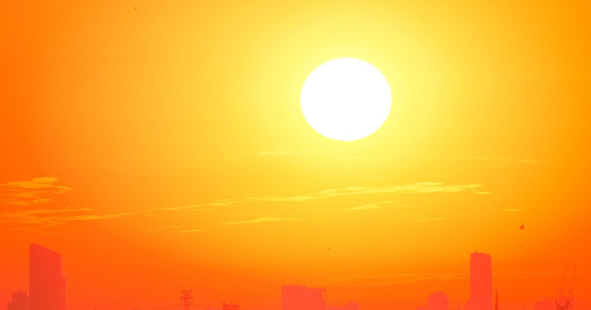 A city skyline silhouetted against a vivid, orange sunset sky.