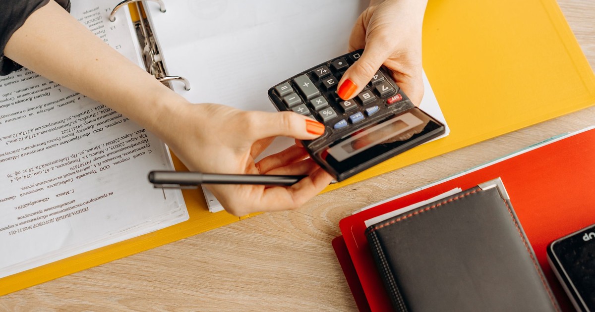 Hands using a calculator at a desk with documents and folders, ideal for finance or accounting themes.