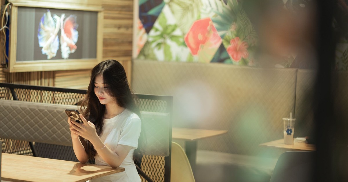 A young woman sits in a cozy Lạng Sơn cafe, engrossed in her smartphone.