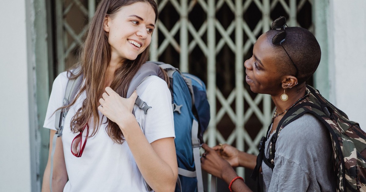 Two women travelers with backpacks sharing a moment in an urban setting.