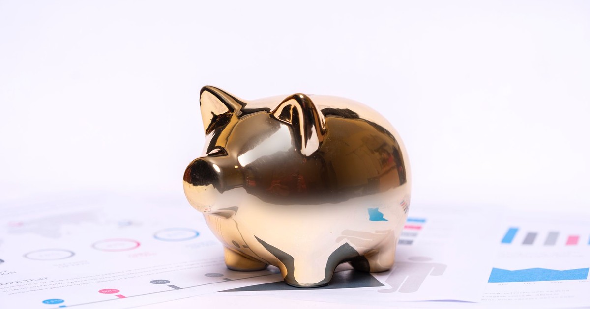 Close-up of a golden piggy bank on financial documents, symbolizing savings and investment.