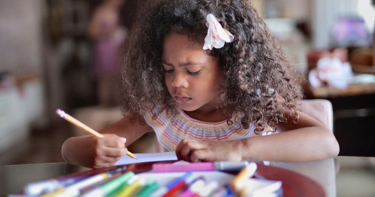 Focused young girl drawing with colored pencils at home. Creative and artistic mood.