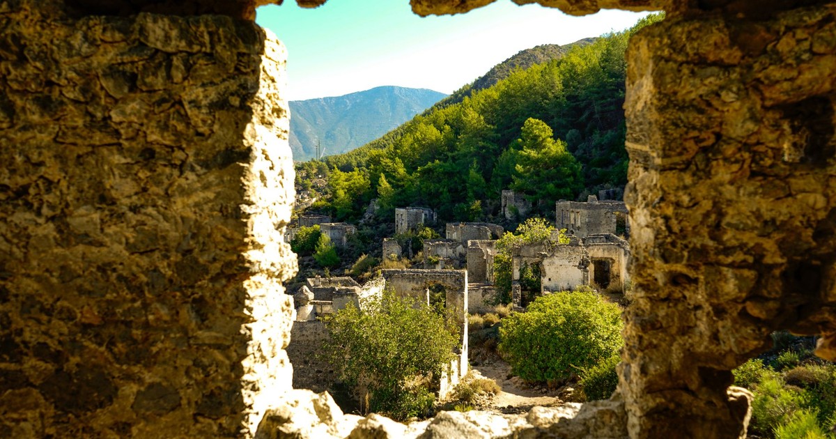 Scenic view of historic ruins in Kayaköy, Turkey framed by stone window.