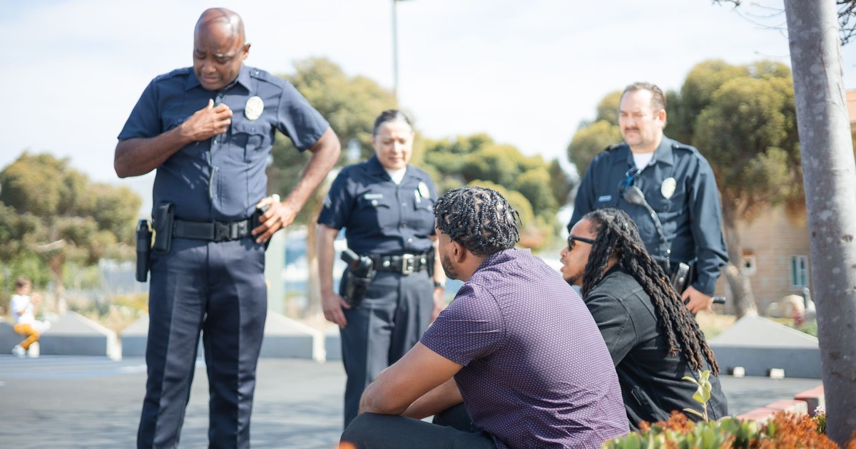 Police officers interacting with individuals on the street in a diverse setting, showcasing community engagement.