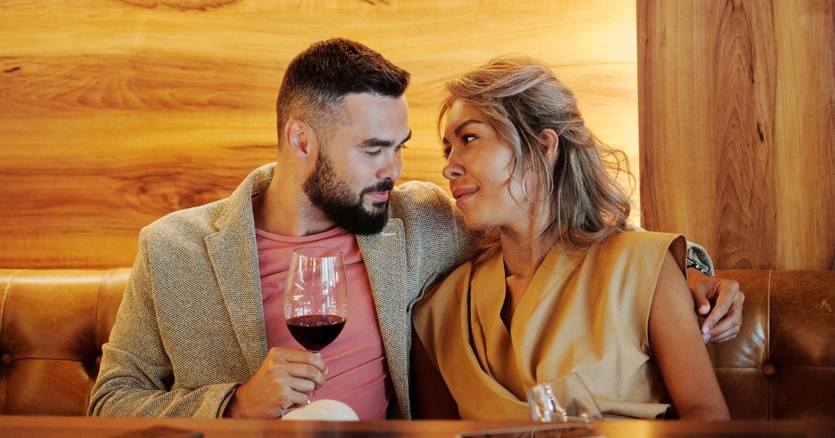 A loving couple sharing a romantic moment with red wine in a stylish restaurant.