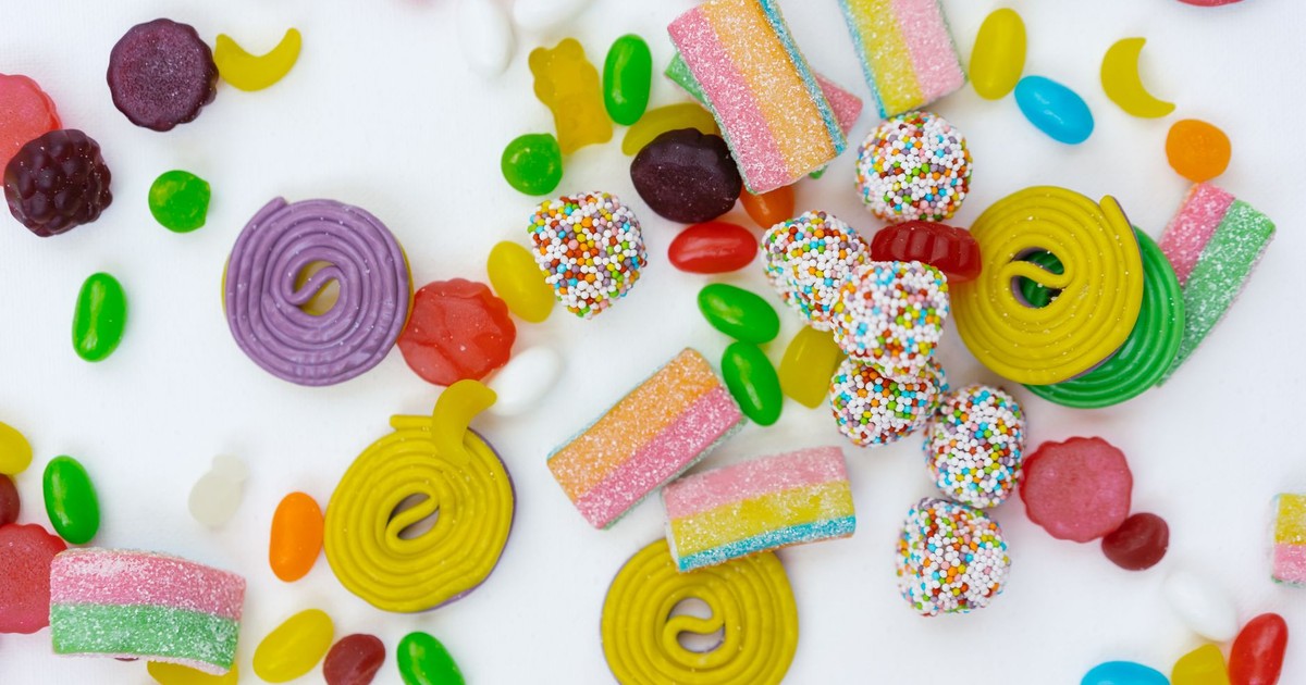 Vibrant variety of colorful candies in a fun flat lay. Includes gummy bears, licorice, and more.