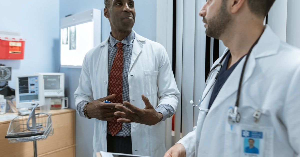 Two doctors in lab coats discussing an X-ray in a clinical setting.