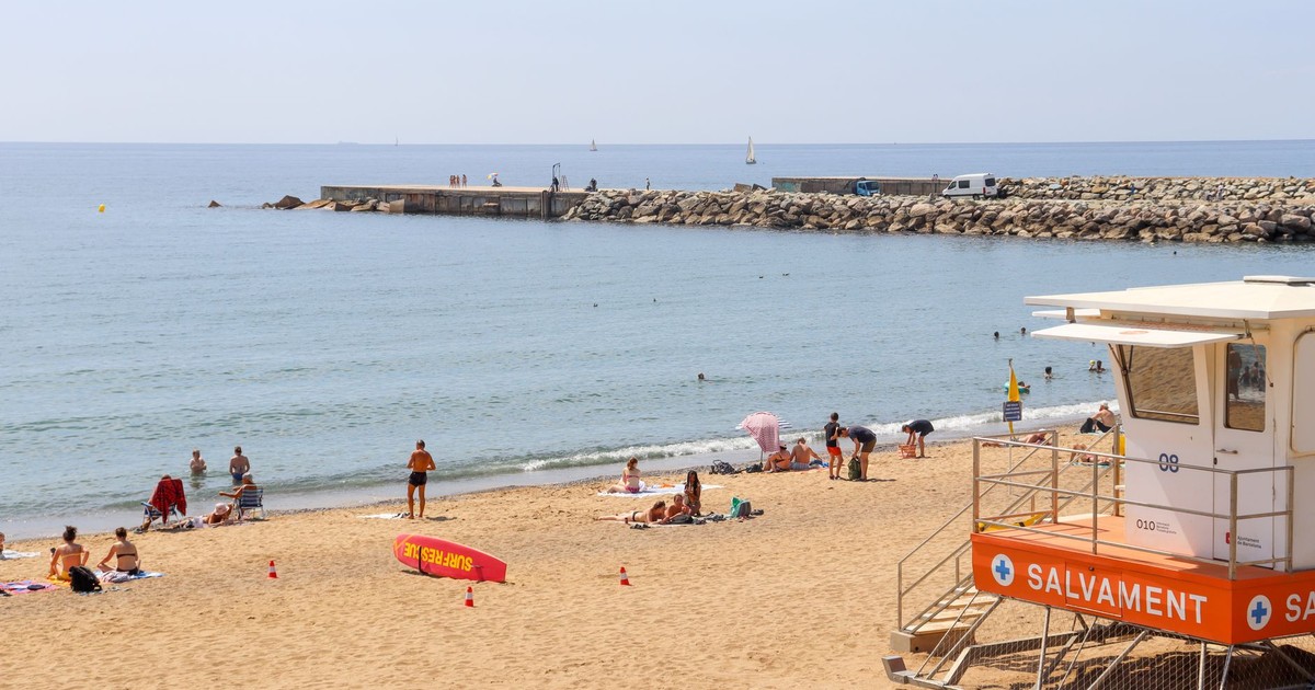Lively beach scene at Barceloneta in Barcelona, featuring a lifeguard tower and sunbathers.