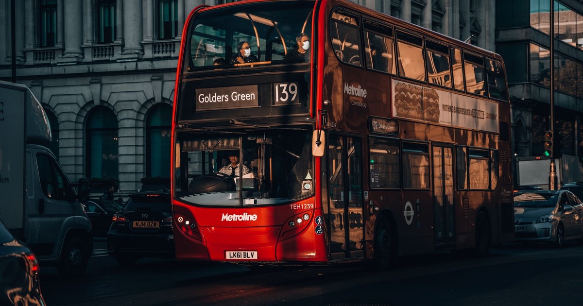 Capture of a red double-decker bus on a street in London, showcasing city transport and architecture.