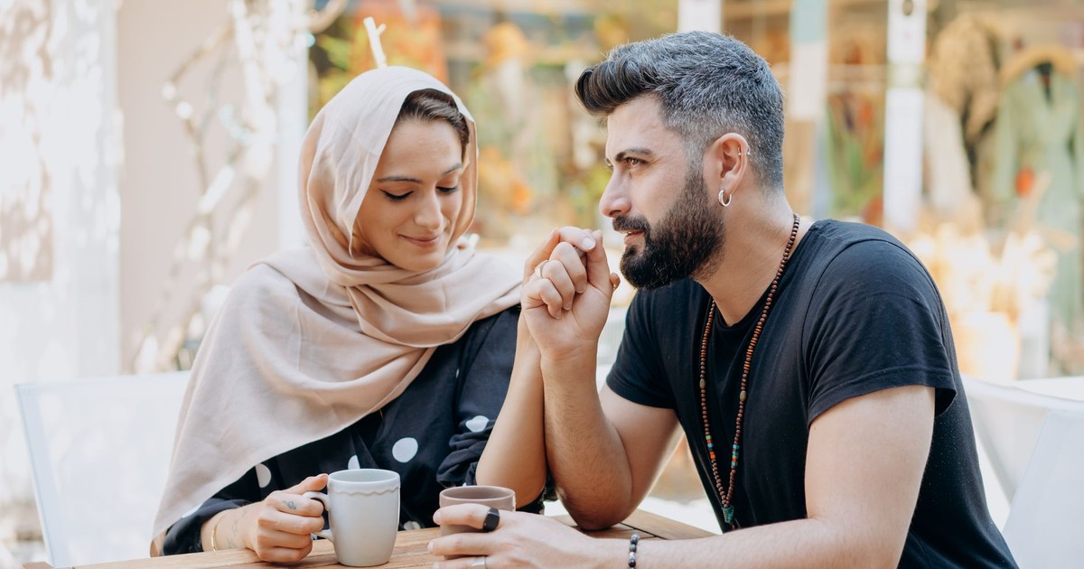 A loving couple holding hands and enjoying a summer coffee date outdoors.