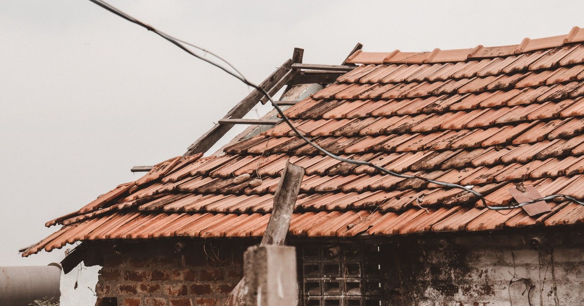 An old rural house with a damaged clay tile roof in Chennai, India, showing signs of decay.
