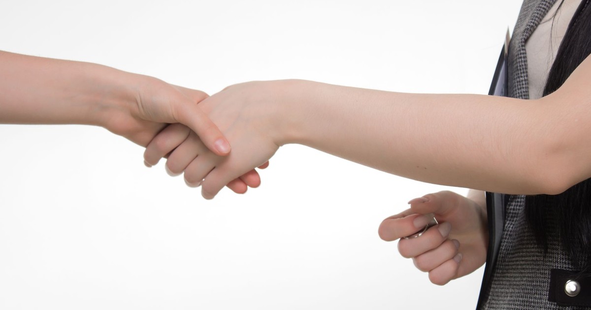 An up-close image of two people shaking hands in a professional setting against a white background.