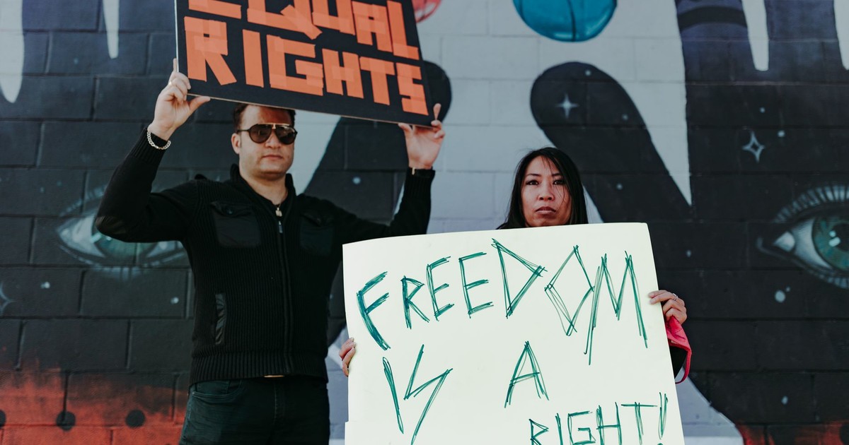 Two people at a protest holding signs for equal rights and freedom.