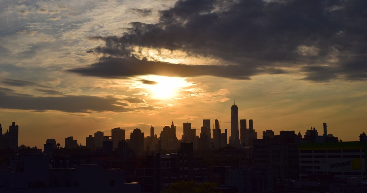 Silhouette of the New York City skyline against a vibrant sunset sky.