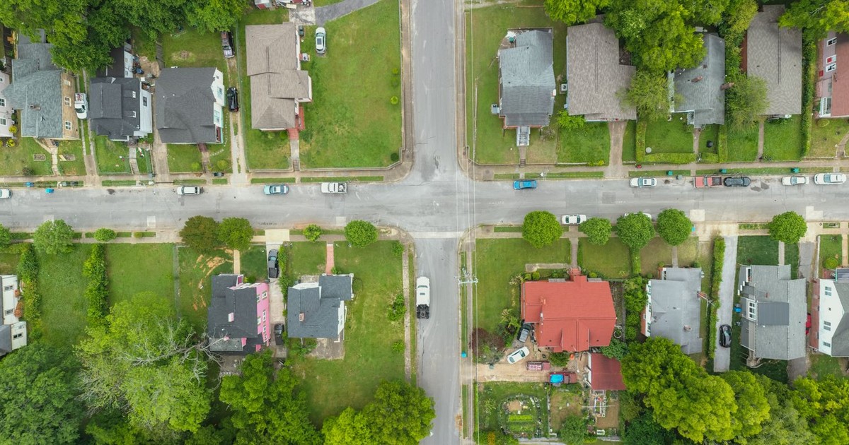 Aerial photo capturing an intersection in a suburban neighborhood with houses and greenery.