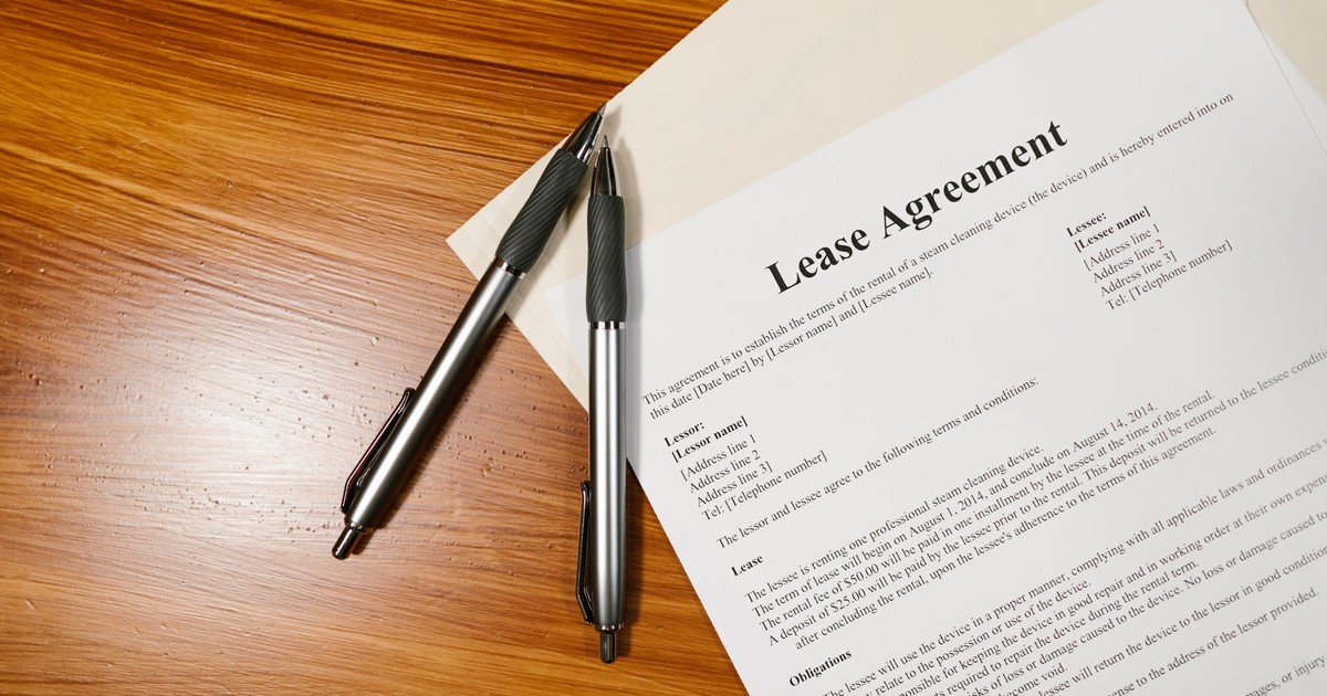 High-angle view of a lease agreement and pens on a wooden desk.