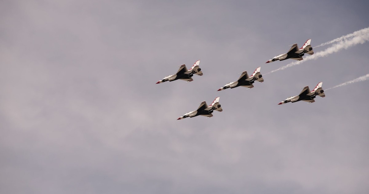 Five fighter jets in formation against a cloudy sky, showcasing precision flying.