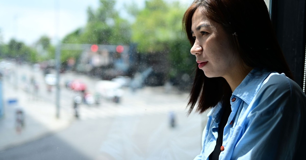 Thoughtful woman gazing out a window to a busy street. Bright day. Indoor contemplation.
